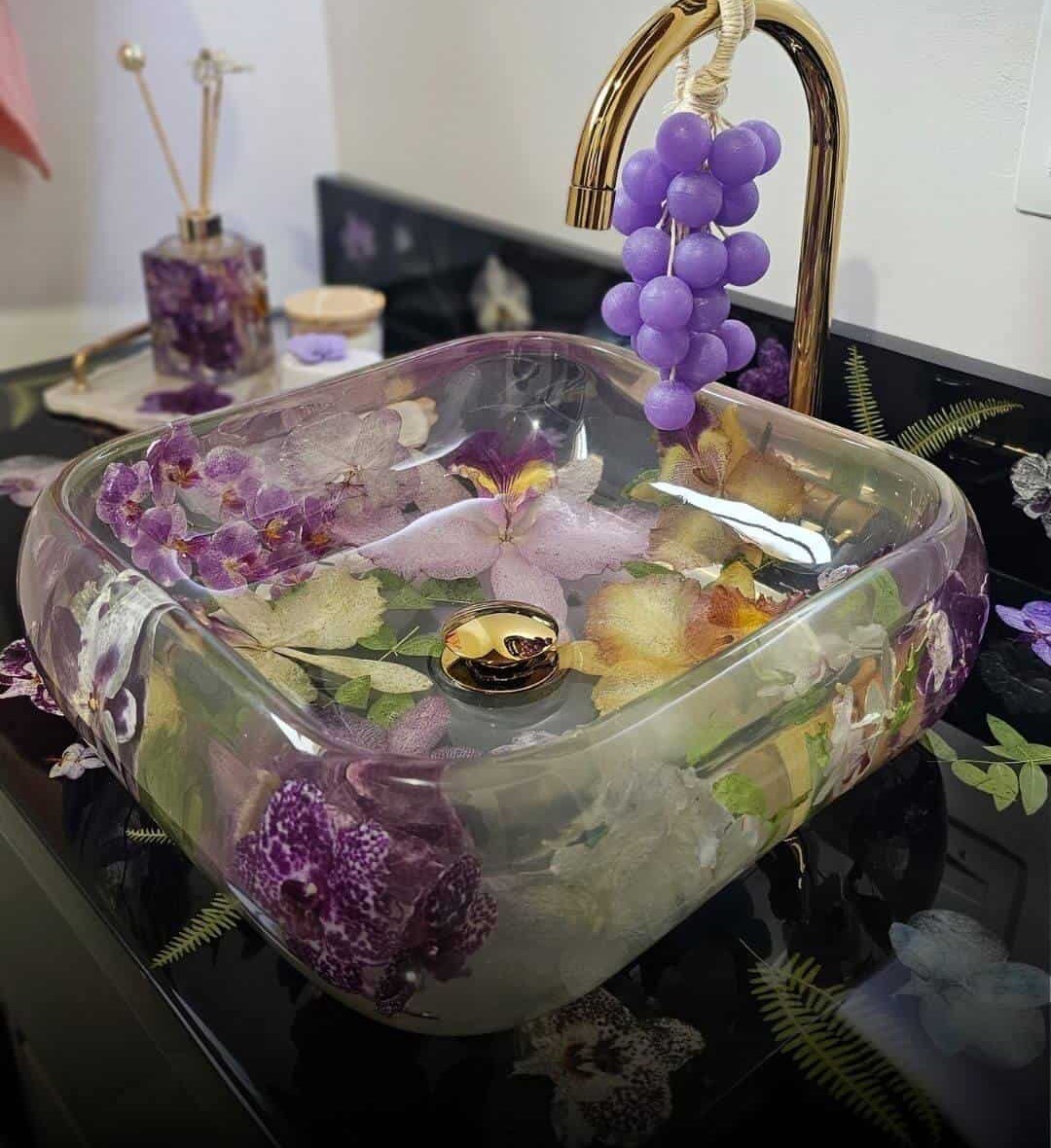 Lavabo de resina transparente con orquídeas naturales y grifería dorada